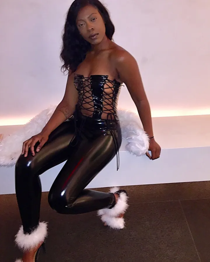 Femme aux cheveux bruns, portant un haut noir, assise, regardant l'appareil