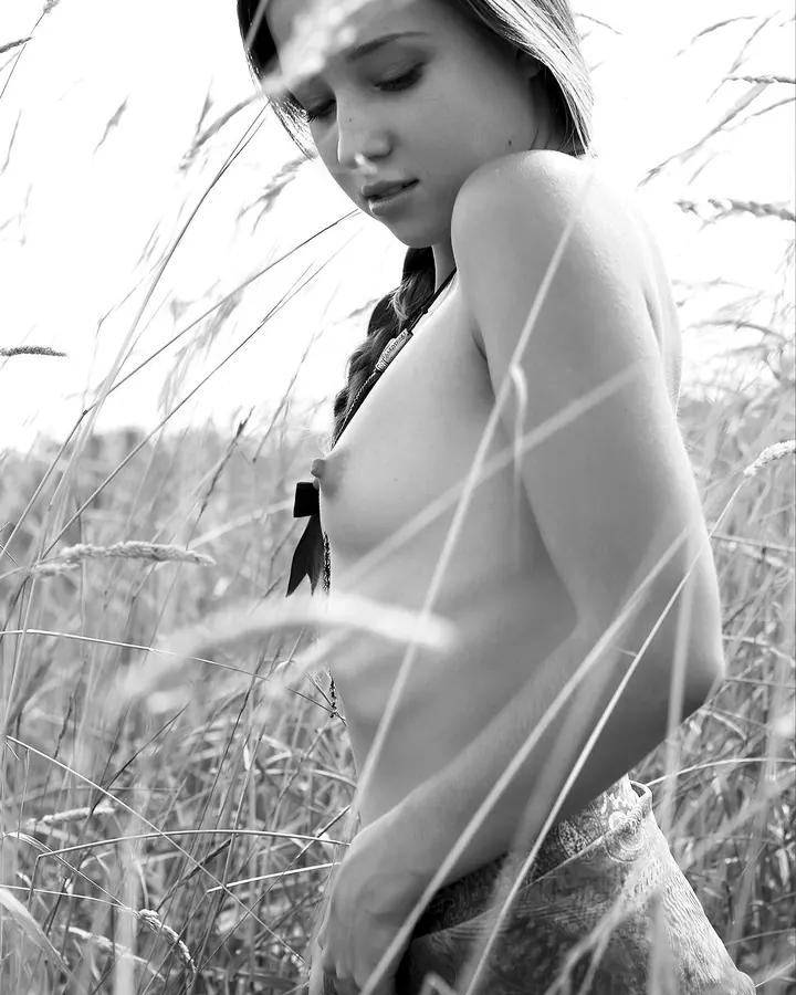 Femme asiatique en bikini orange, posant devant un grand miroir baroque, les yeux fermés et un sourire discret.