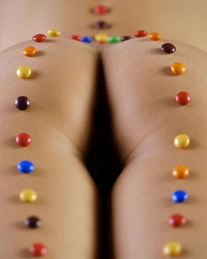 Plan rapproché sur les fesses d'une femme avec des perles colorées disposées en ligne.