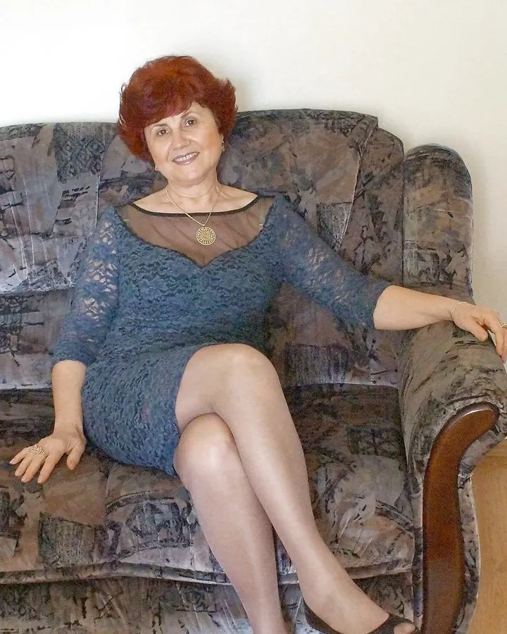Femme aux cheveux roux, peau blanche, regard direct, pose assise sur un canapé, ambiance chaleureuse