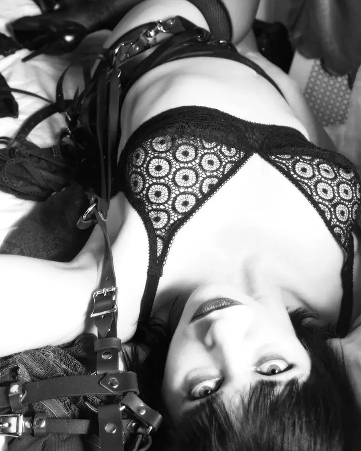 Femme en lingerie noire, posant de profil, les yeux fermés, dans un cadre sombre