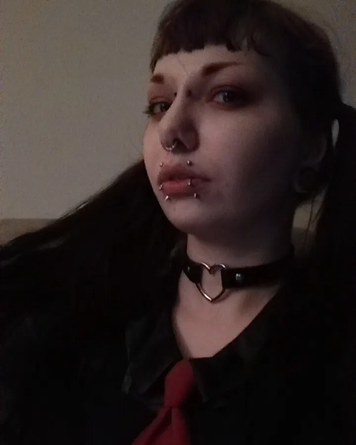 Femme aux cheveux noirs, portant un haut blanc, allongée sur un canapé, regardant vers la caméra
